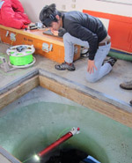 Colin Ho watches MSLED through a hole in glacial ice before it is submerged.